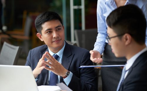 Handsome young businessman having meeting with partners in cafe